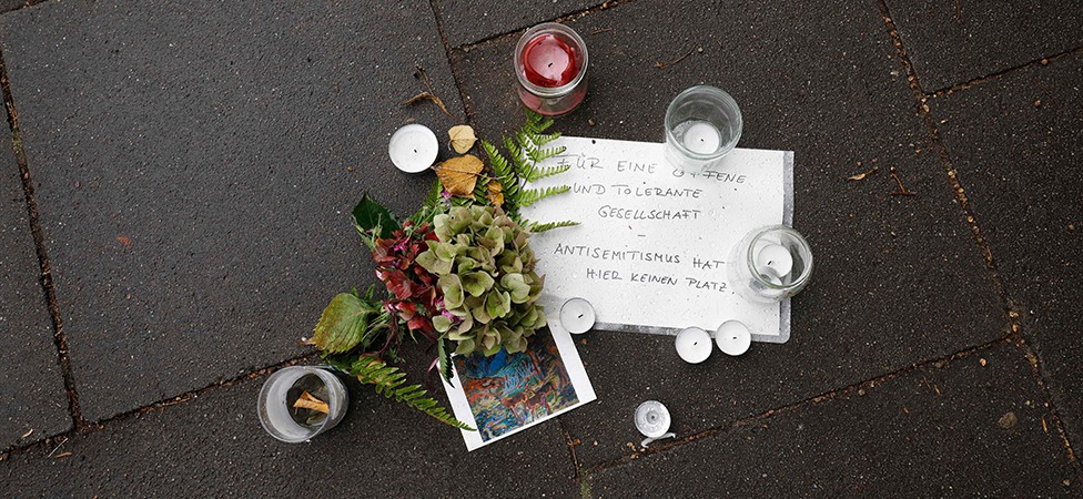 Blommor, ljus och en handskriven lapp vid platsen där en man dagen innan blivit grovt misshandlad
